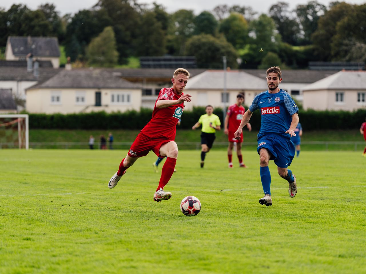 heros-img Action shot of soccer players competing on a lush green field outdoors.